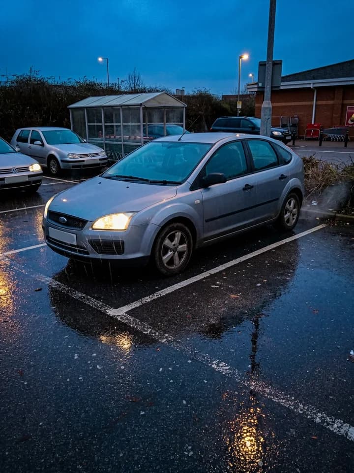 The Getaway: a parked car peels out of its bay into the rain at dusk. concept preview